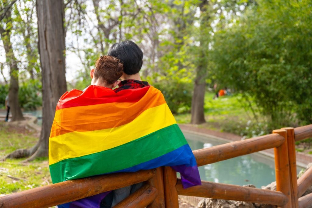 Young person wearing a rainbow flag representing non-binary identity during a legal name change in the UK