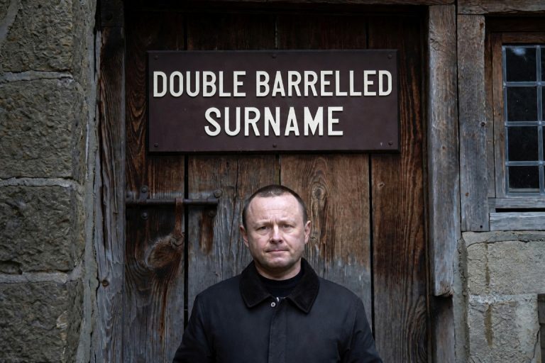 Man with a double barrelled surname under a sign